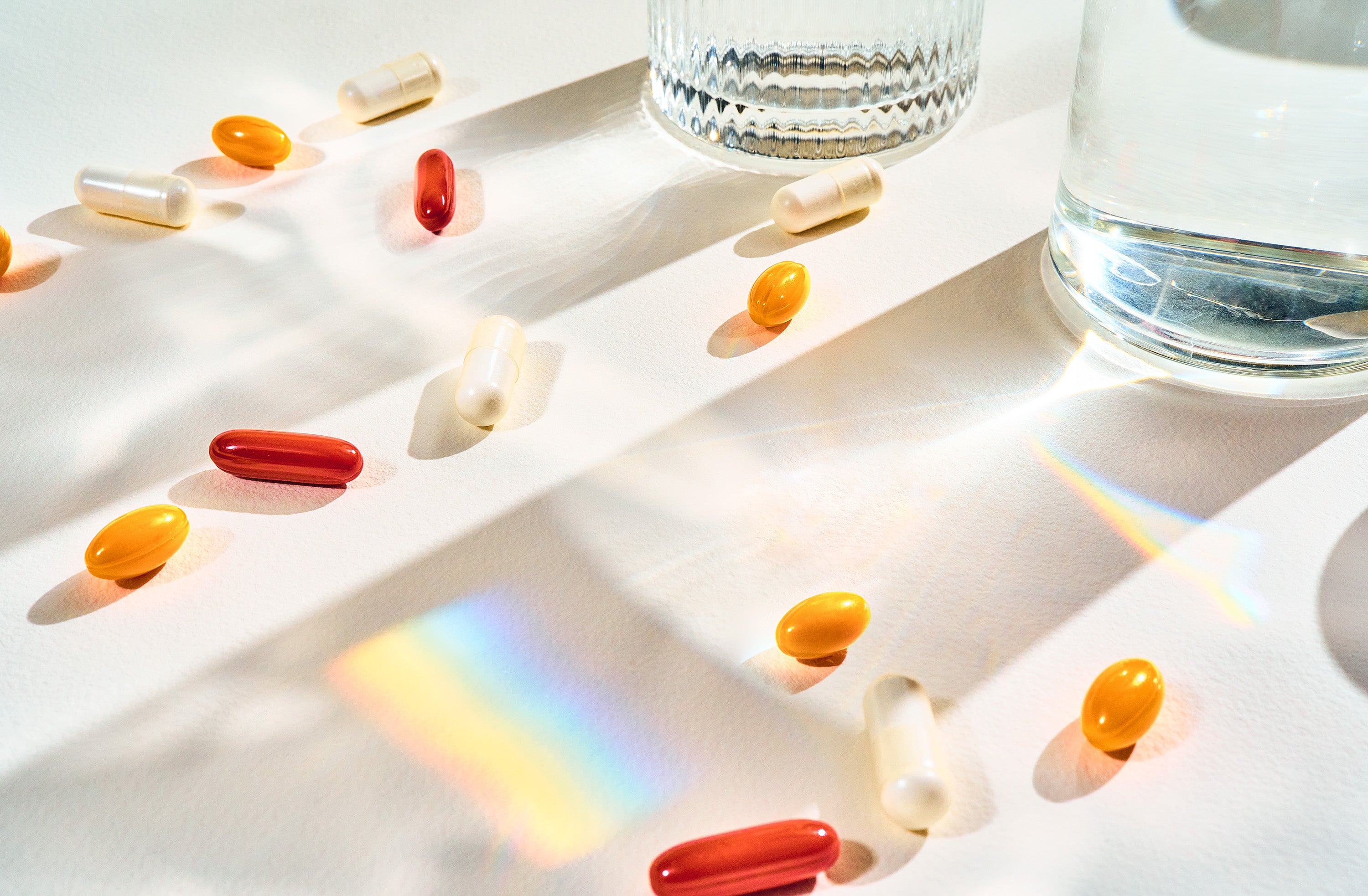 Smarter Nutrition capsules and softgels next to a water glass